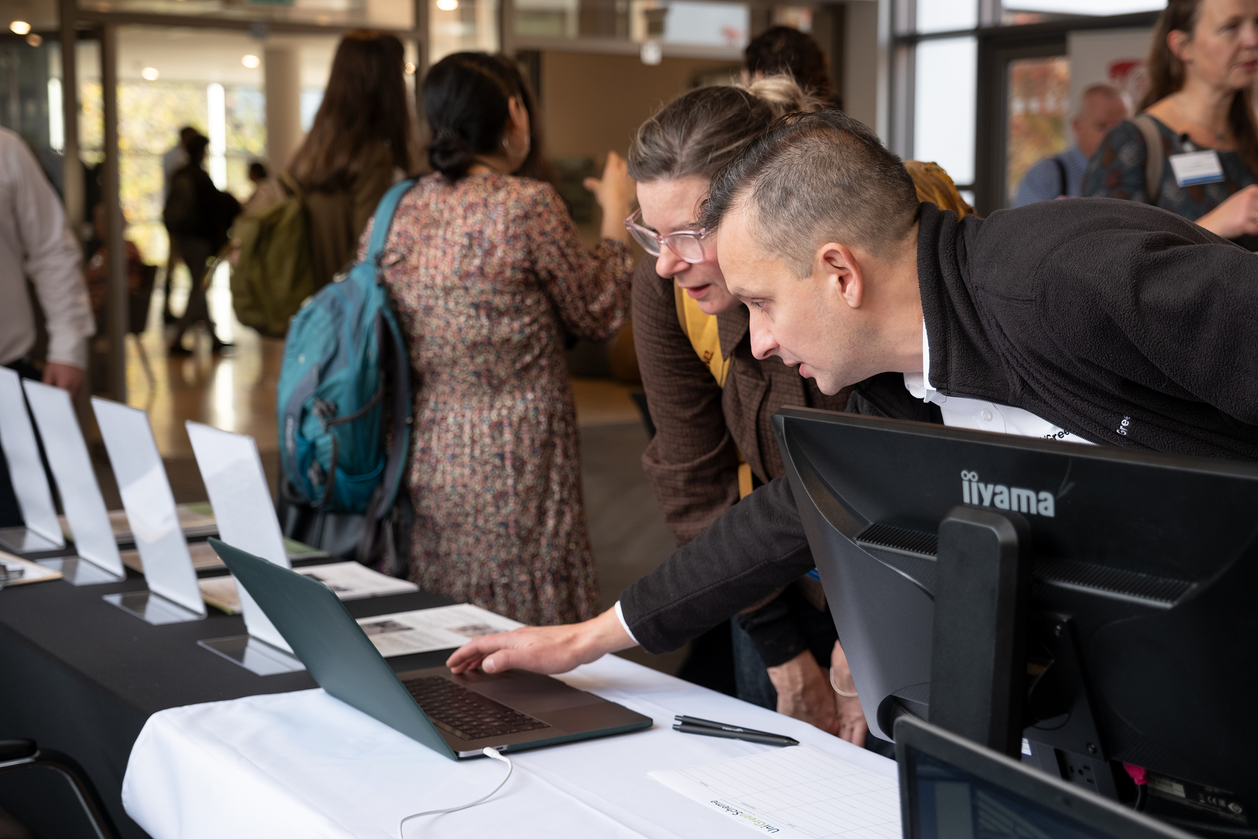 Two people look at a laptop, scrutinising information 