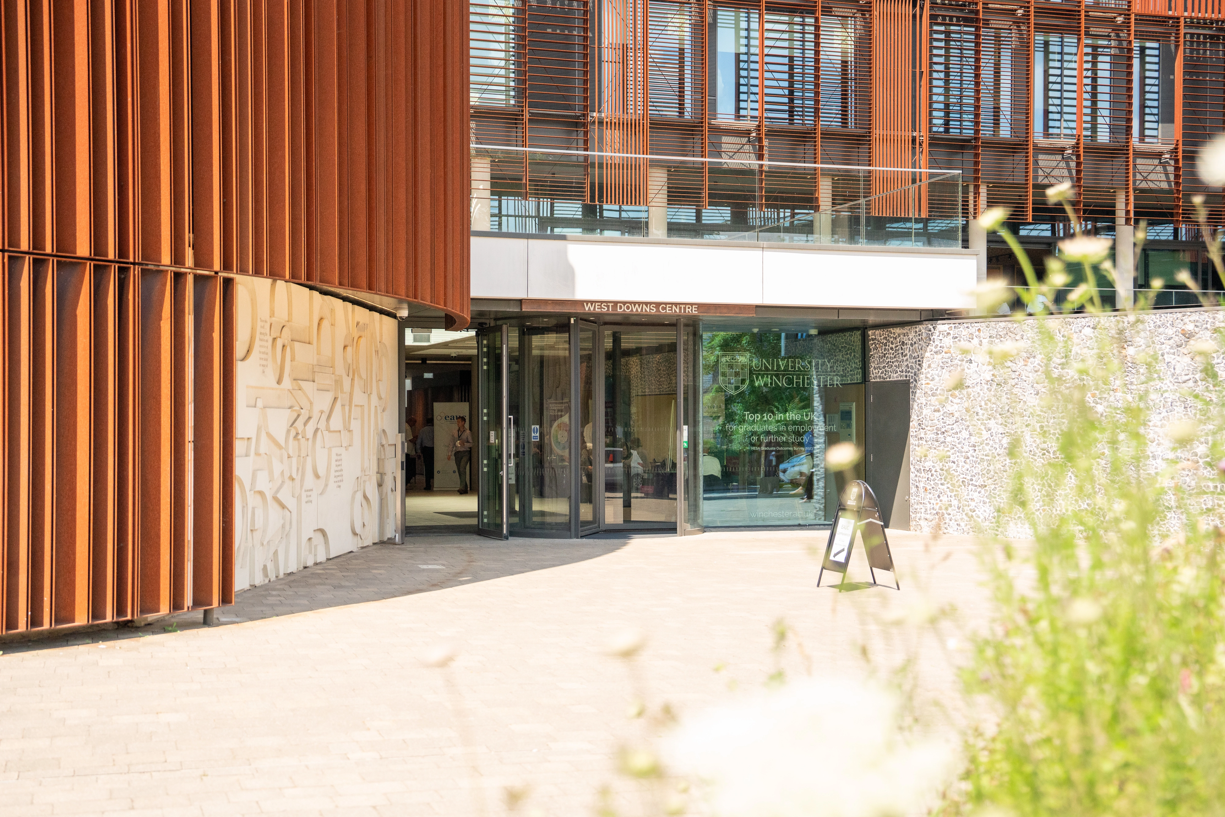 A green plant with bins and a university building in the background 