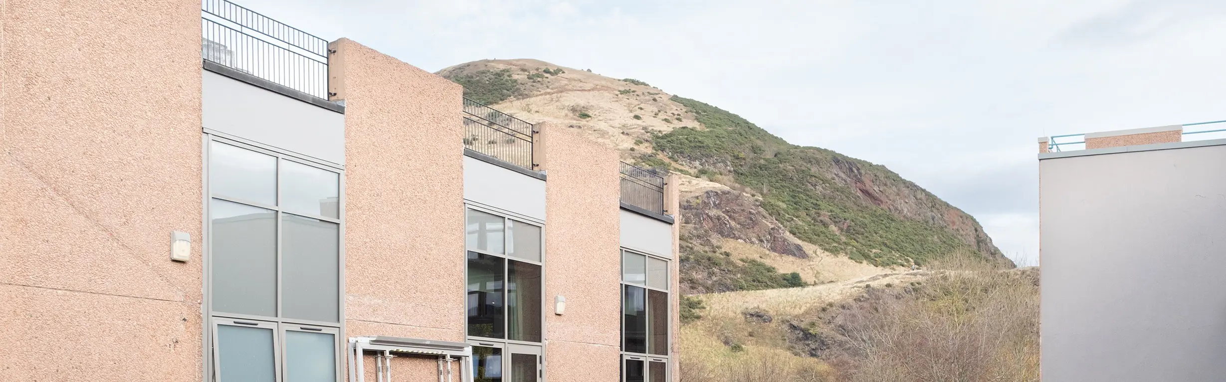 A university building with a view of a hillside in the background. 