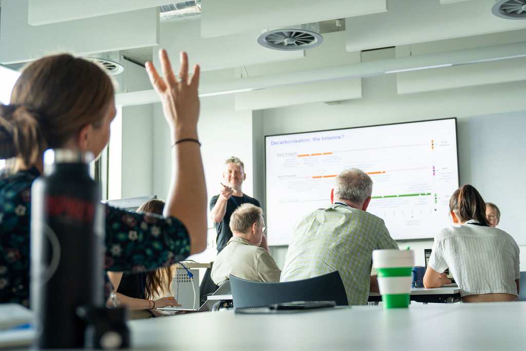 A woman puts up her hand in a classroom 